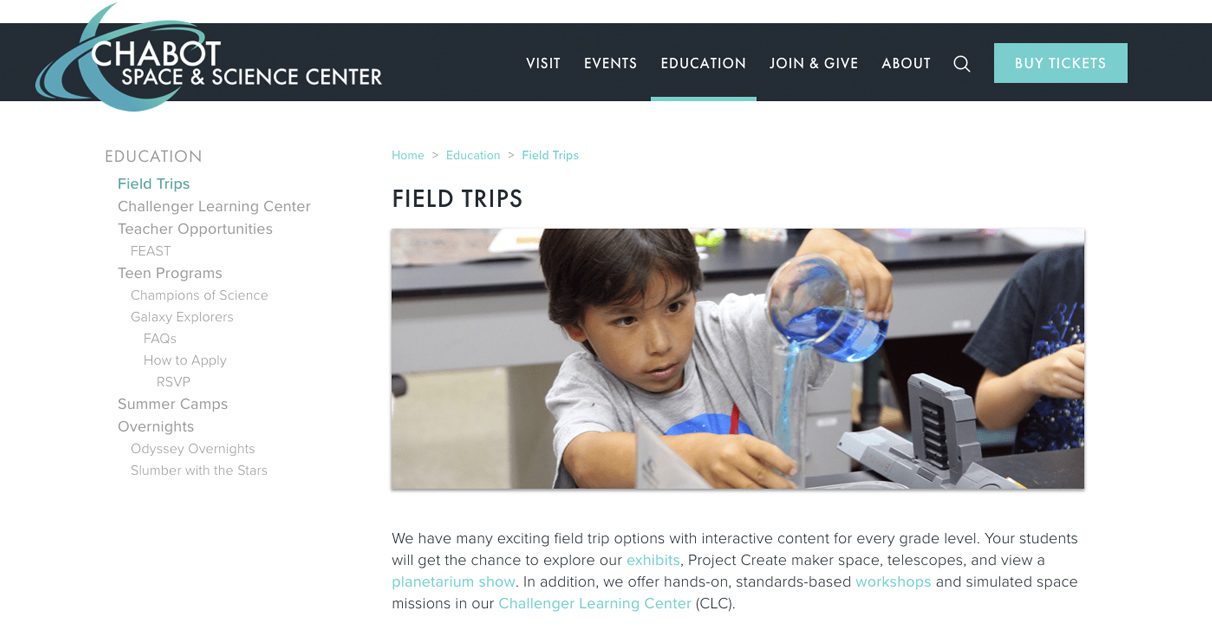 A young boy pours liquid from a beaker into a measuring cup during a hands-on science activity at the Chabot Space & Science Center’s field trip program, with lab equipment and supplies visible on the table.